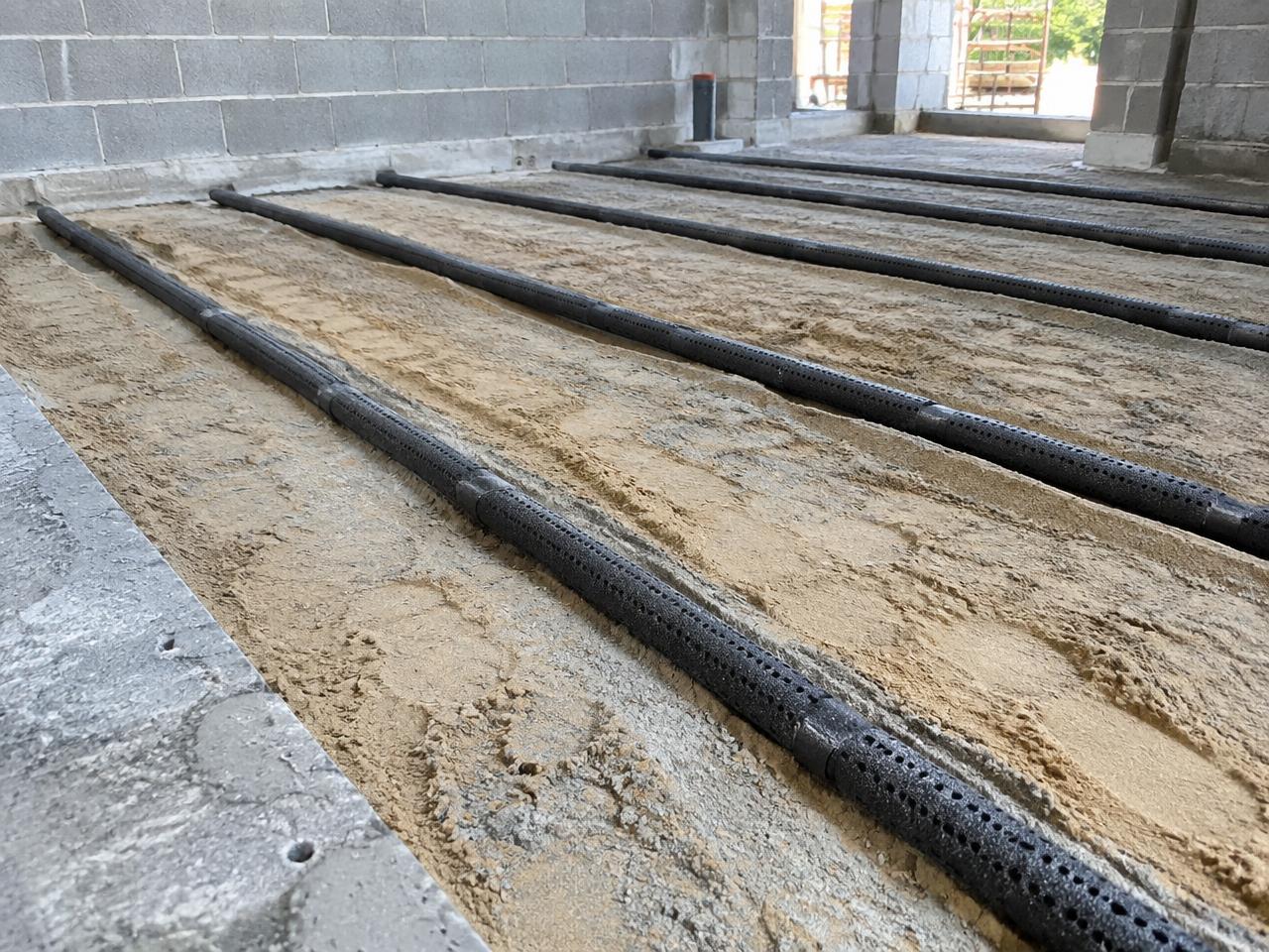 Black porous reticulation pipes laid on a prepared floor bed